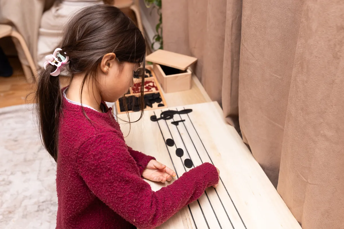 Enfant manipulant une portée musicale en bois Serclet